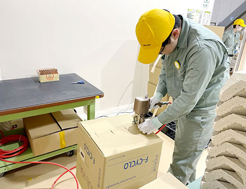工場内で作業員が段ボールを組み立てている様子を撮った写真です